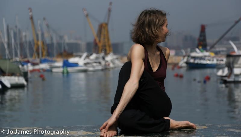 a yoga pose with the Hong Kong harbor as background
