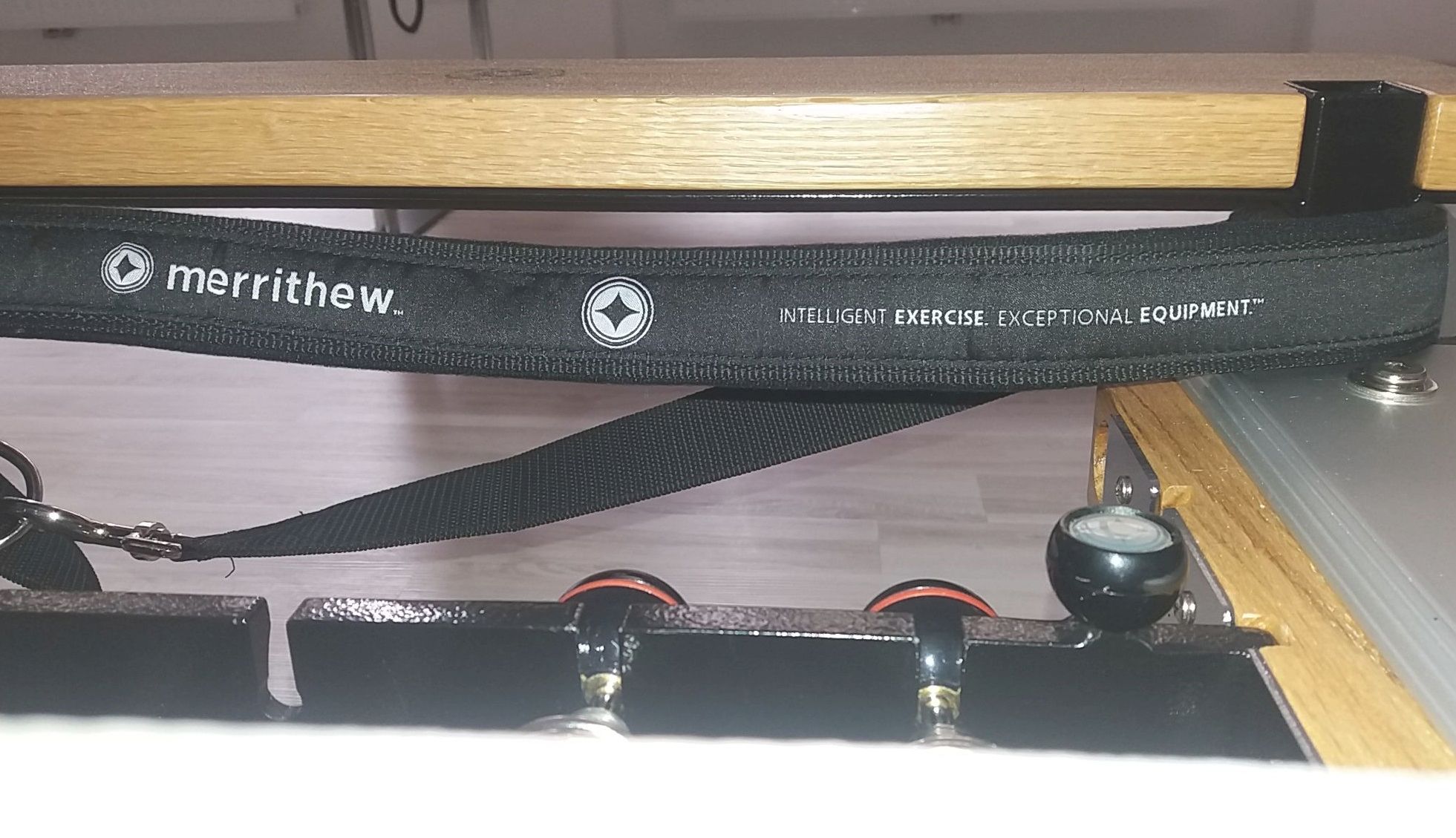 The edge of the Pilates Reformer showing a strap and gear bar