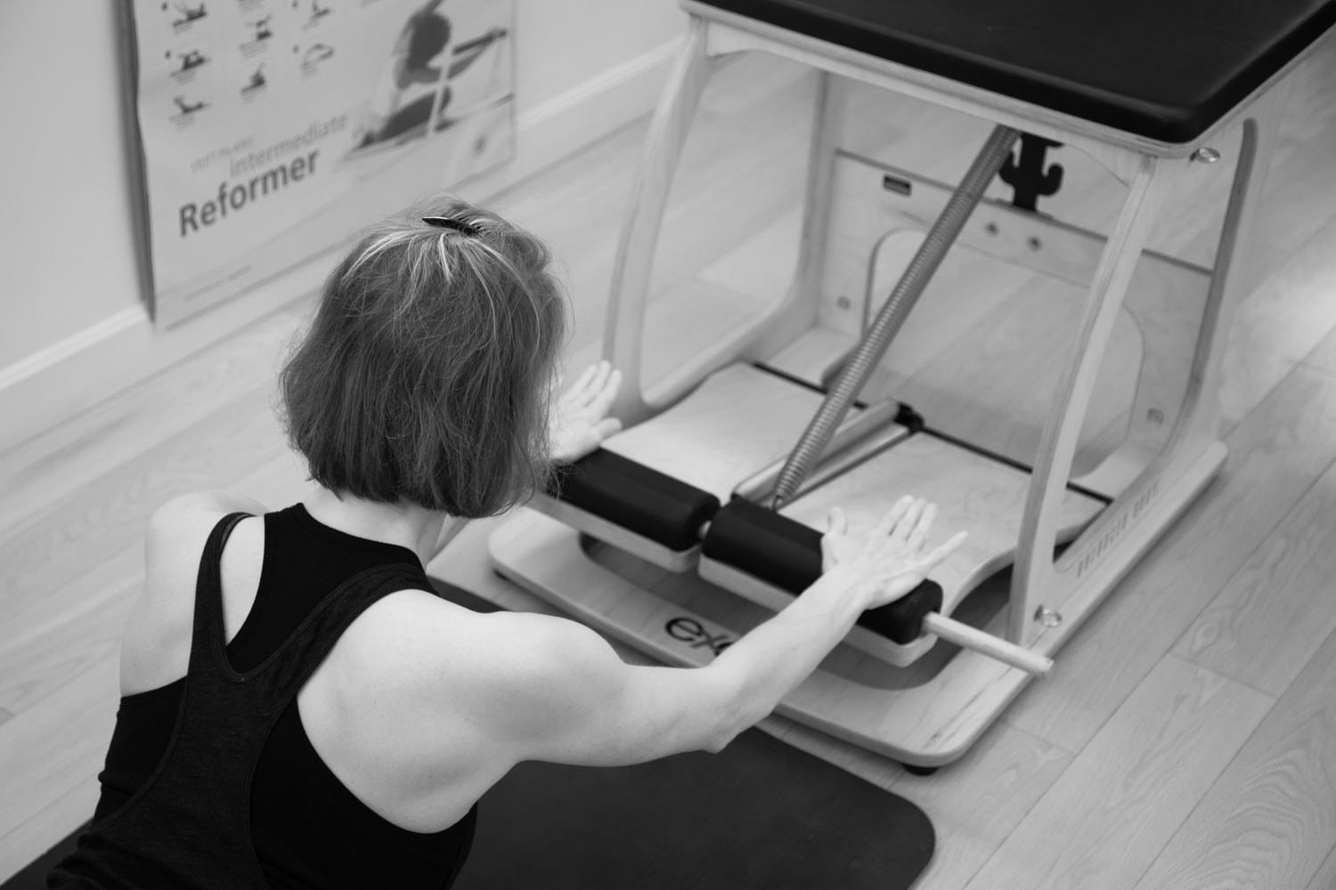 a Pilates instructor demonstrating a Swan Dive exercise on Chair