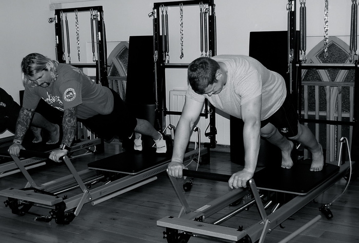 men rugby players performing exercise on Pilates Reformer