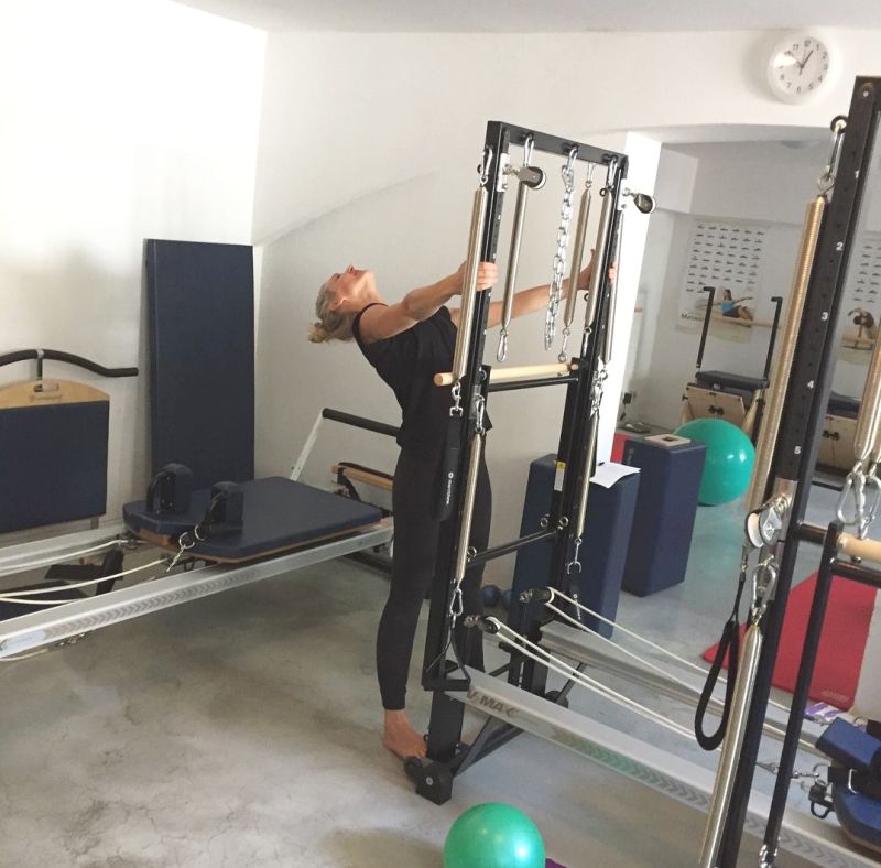 Pilates instructor demonstrating a variant of Spread Eagle exercse on STOTT Tower Trainer