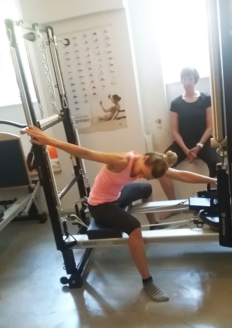 Pilates instructor demonstrating Saw Exercise on Reformer